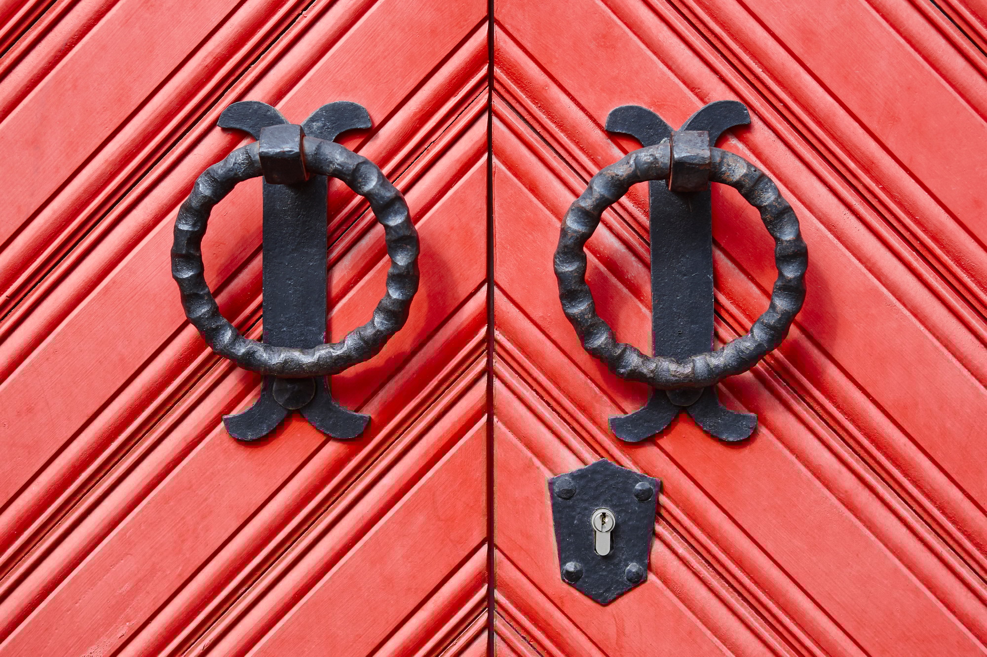 Antique metallic door knob on a red wooden doors. Horizontal